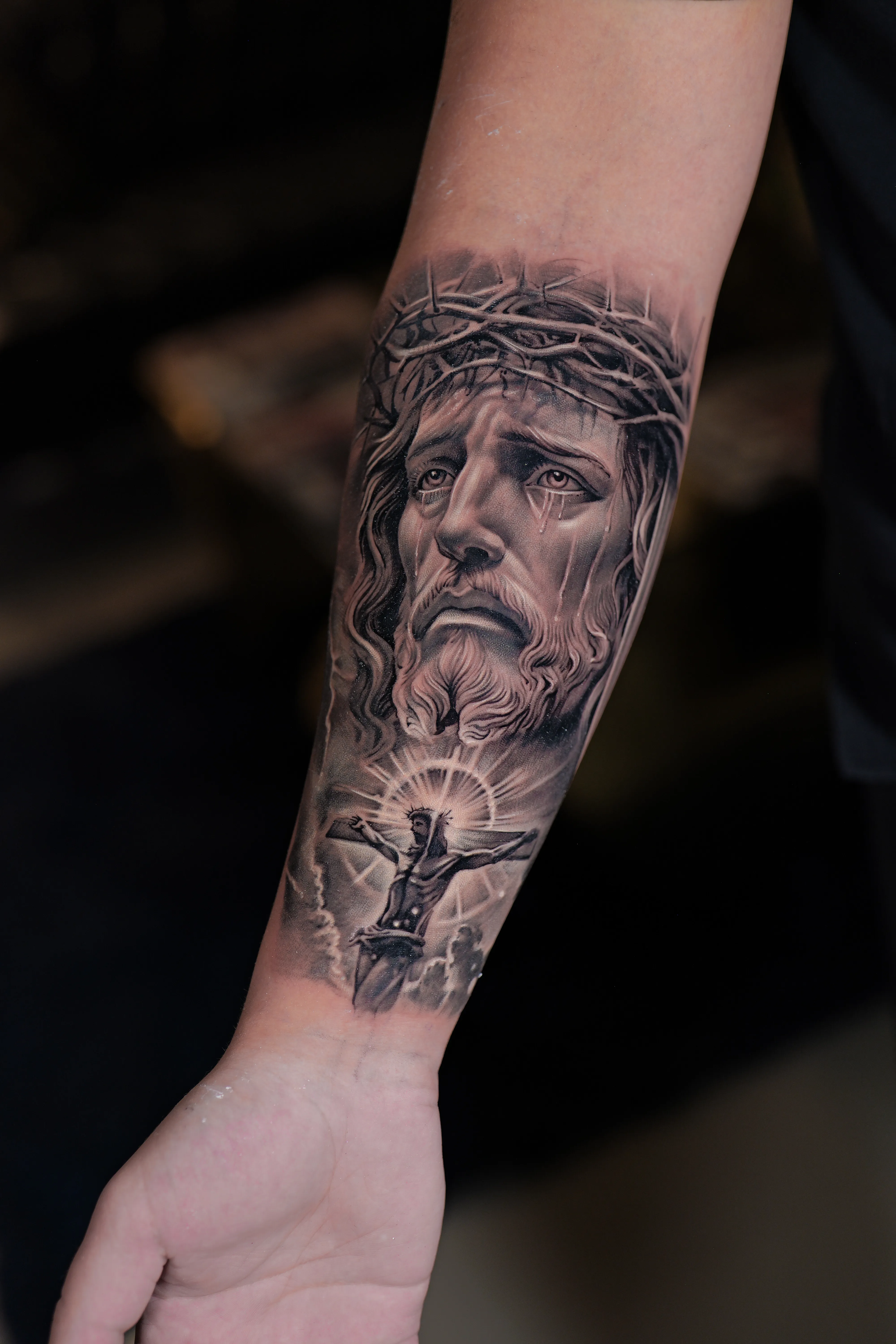 Black-and-grey realism of Christ with a small, finely detailed crucifixion scene below — TKOTATTOO Fort Lauderdale